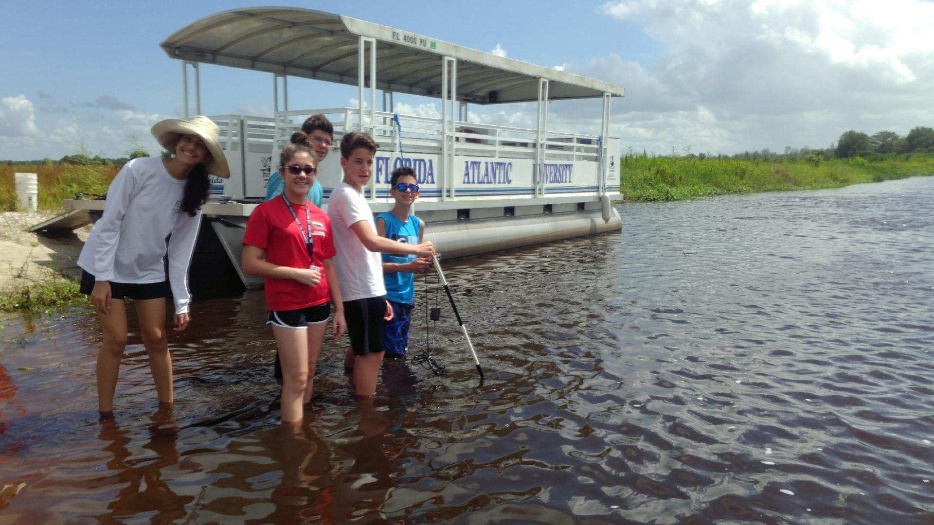 Highschool students in front of boat